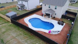 a curved, custom inground vinyl pool in a backyard, as Kirk's Pool and Hearth puts the finishing touches on its installation