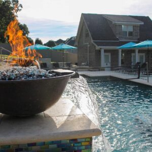 a beautiful fiberglass swimming pool in Spartanburg SC shimmering in the afternoon sun, with a flaming brazier feature in the foreground