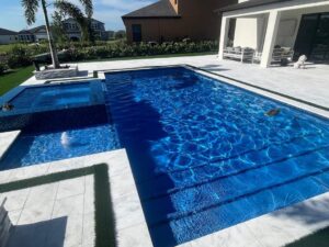 a custom inground pool installed by Kirk's Pool and Hearth. the water is a rich, deep blue and it shimmers in the afternoon light