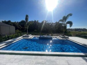 a rich blue inground pool from Kirk's Pool and Hearth, shimmering in the afternoon sun