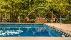 a custom fiberglass pool installed by Kirk's Pool and Hearth, with two fountain water features casting water in an arc into the pool