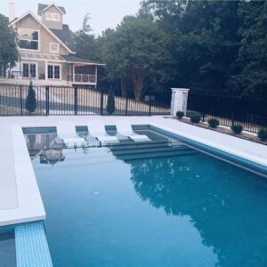 a gorgeous inground pool built by Kirk's Pool and Hearth with a two-story house in the background